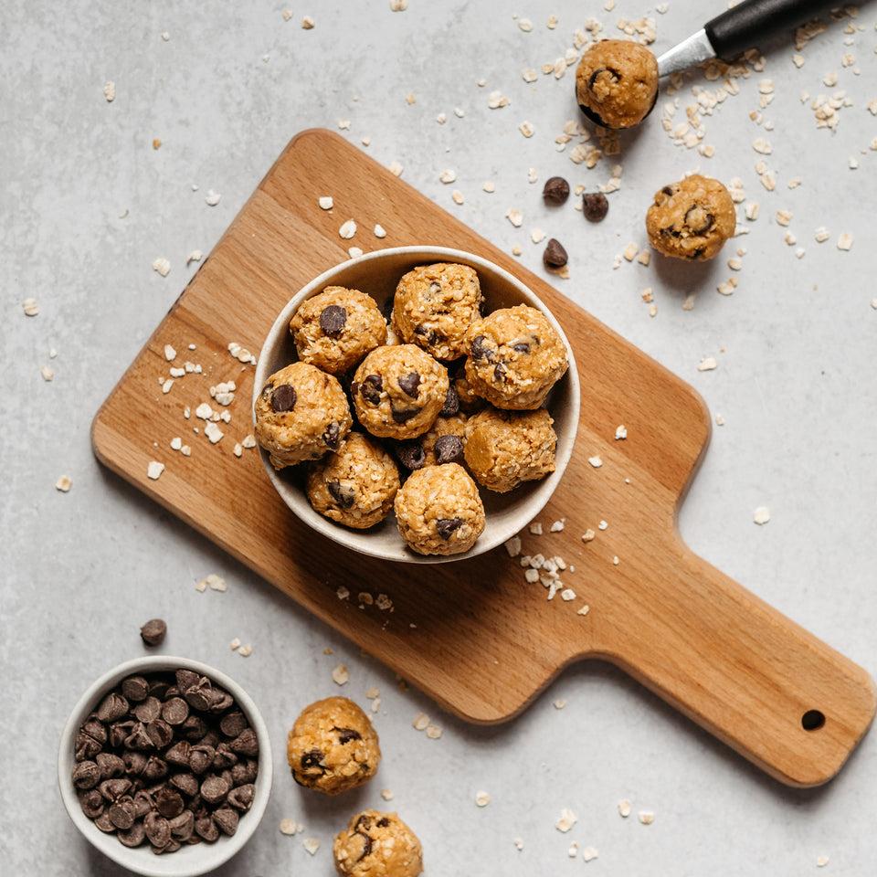 Chocolate chip protein balls in a bowl on a cutting board.